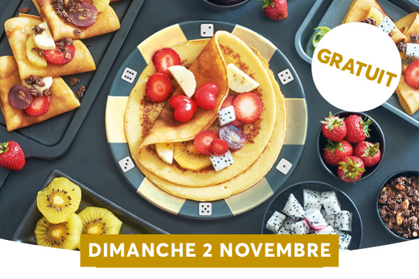 Une assiette de crpes garnies de fruits colors est entoure de petites collations et de fruits frais sur une table de mousse  motif jets de ds, avec un badge GRATUIT. Un plateau de desserts et de fruits est dcor de dominos et de morceaux de chocolat, tandis quun ruban en bas annonce DIMANCHE 2 NOVEMBRE et une tiquette GRATUIT. Lambiance festive et gourmande est accentue par les fruits en tranches, les morceaux de dragon et les ds, prte  attirer les visiteurs le dimanche 2 novembre.