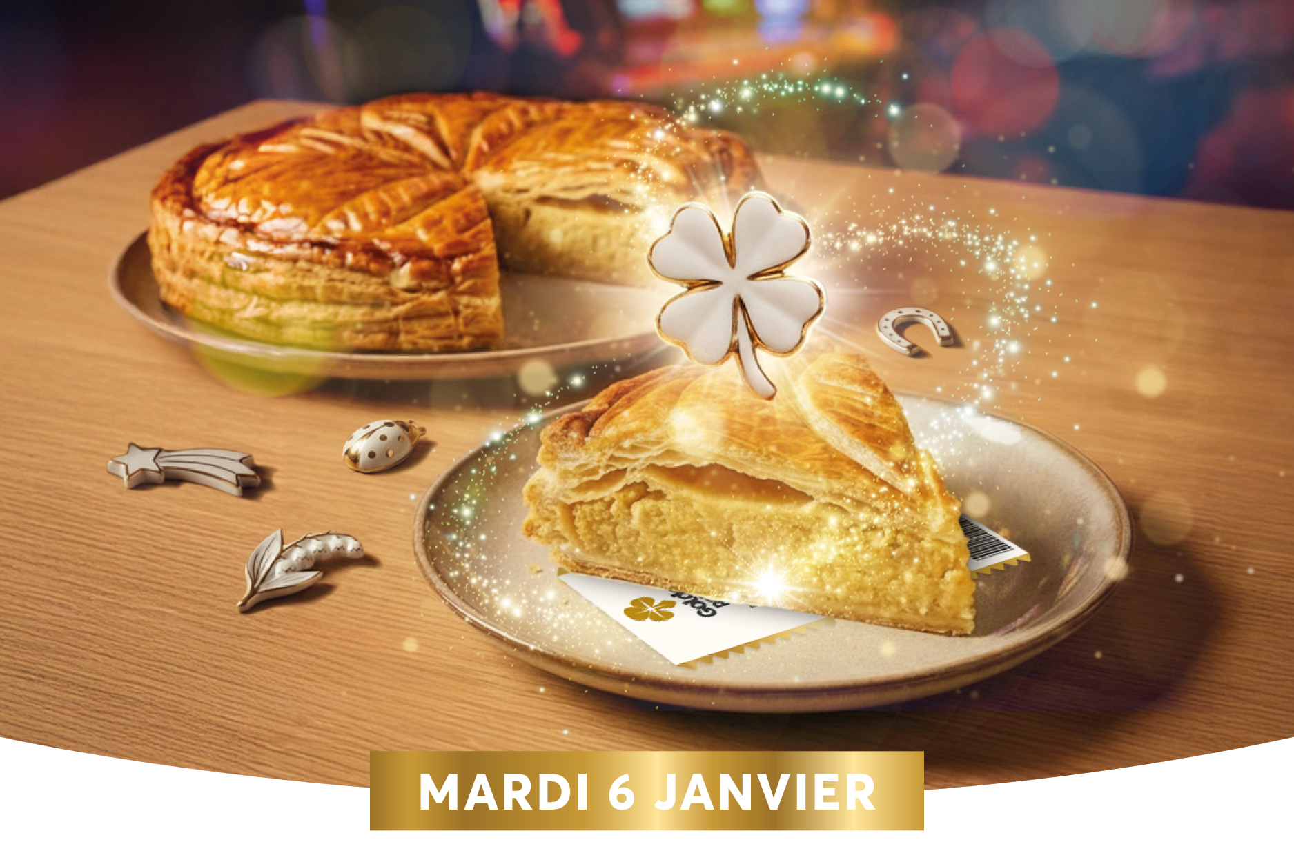 Le g�teau des rois tr�ne sur une assiette en bois, d�cor� d�un tr�fle en sucre et entour� de petits ornements argent�s, avec des poussi�res scintillantes qui ajoutent une touche magique. Le bandeau en bas indique la date �Mardi 6 Janvier�, sugg�rant une c�l�bration ou un �v�nement sp�cial autour de l��piphanie.