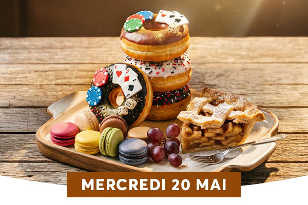 Un plateau en bois rassemble une g�n�reuse s�lection de desserts : une pile de trois donuts surmont�s de jetons de poker et de cartes � jouer, des macarons color�s, une part de tarte aux pommes et une grappe de raisin, le tout sur fond de bois flout�. L'ambiance est chaleureuse et ludique, m�lant gourmandise et clin d'�il aux jeux de casino.